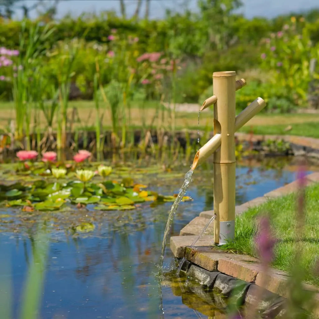 Bamboo water fountain by a pond with lily pads in a landscaped garden