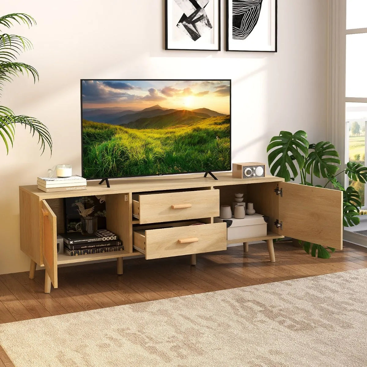 Modern wooden TV unit with open drawers and doors, flat-screen showing sunset landscape, indoor plants