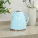 Light blue electric kettle on a kitchen counter with a plant and utensils in the background.