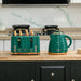Green ceramic toaster and kettle on a kitchen counter with a marble backsplash.