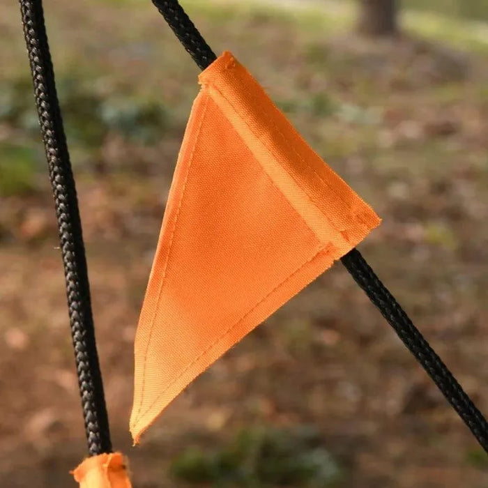 Close-up of orange fabric triangle on black ropes, outdoor garden tree swing detail