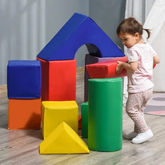 Toddler playing with colorful foam geometric learning toys on a wooden floor indoors.