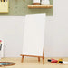 Blank stretched canvas on wooden easel with paint tubes and art supplies in studio