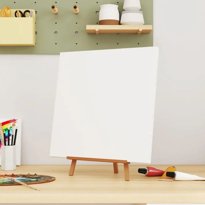 Blank stretched canvas on easel with paint tubes and brushes in an artist workspace