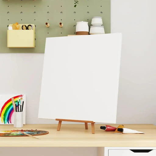 Blank stretched canvas on easel with paint tubes and brushes in artist workspace