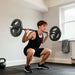 Man performing a barbell squat in a home gym setting.