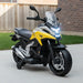 Yellow and black Honda kids' electric ride-on motorcycle with training wheels on driveway