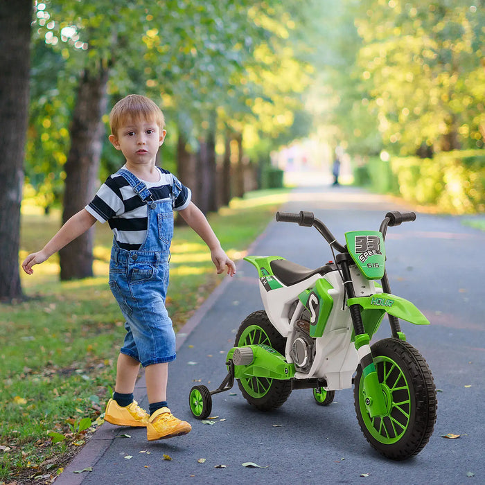 Child with a green and white toy motorcycle on a path in a park