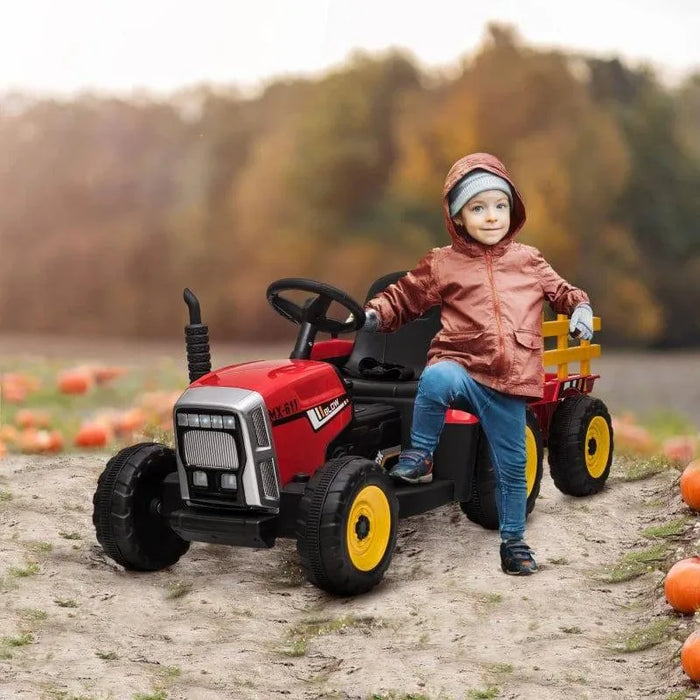 Child on red 12V electric ride-on tractor with detachable trailer in a pumpkin field