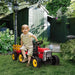 Child on red 12V kids electric ride-on tractor with detachable trailer in garden