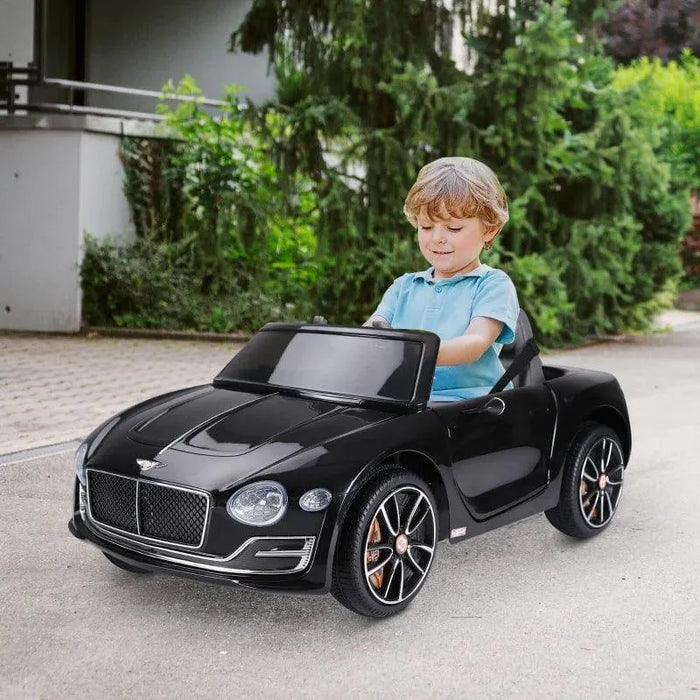Child driving black 12V Bentley GT kids electric ride-on car outdoors with LED lights