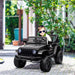 Child driving black 12V kids off-road ride-on car with working doors outdoors