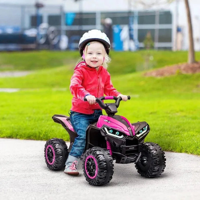 Child riding pink 12V kids ride-on quad ATV with helmet outdoors on grass