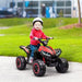 Child riding red 12V kids ride on quad ATV bike with LED headlights outdoors