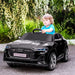 Child driving a black 12V Audi e-tron Sportback kids' electric ride-on car outdoors