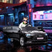 Child in sunglasses driving black Audi e-tron kids electric ride-on car with open door