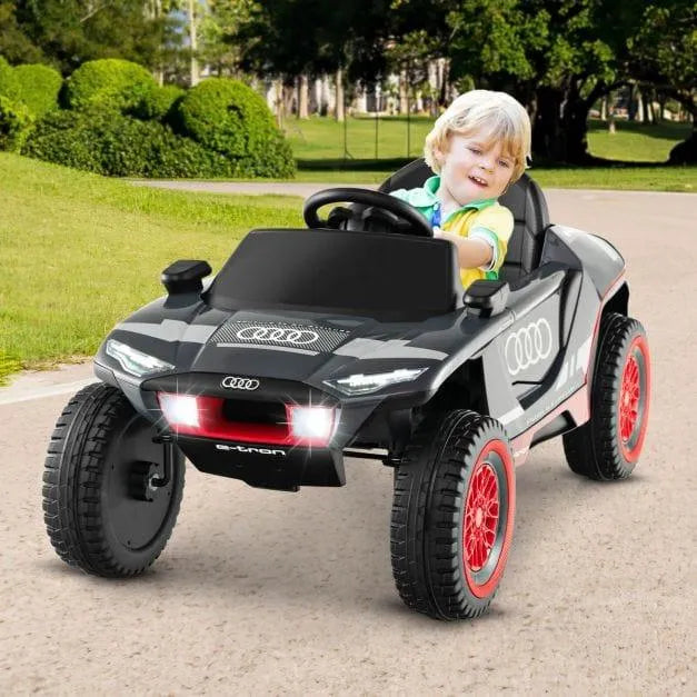 Child driving 12V Audi e-tron kids electric ride-on car with lights on outdoors