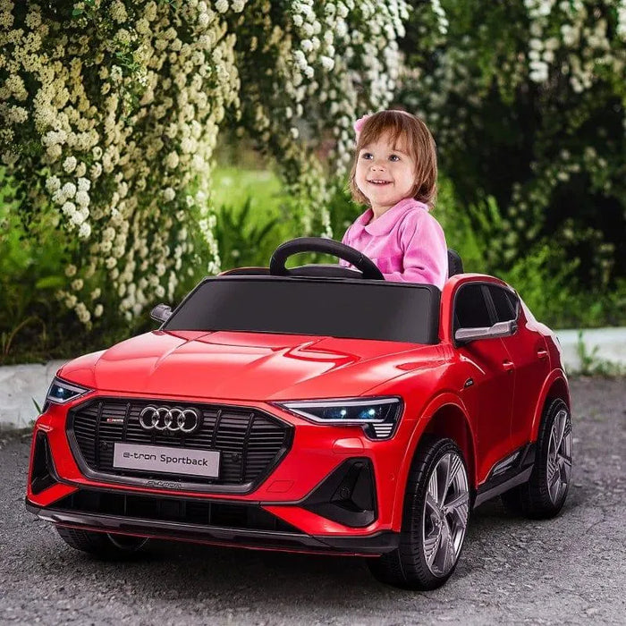 Child driving red Audi e-tron Sportback kids ride-on car with LED lights outdoors