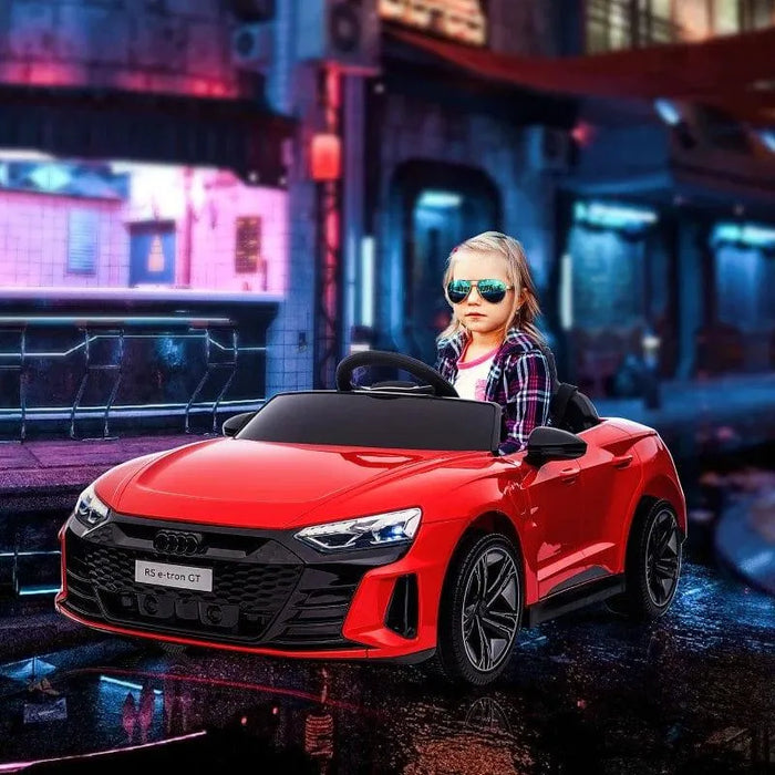 Child driving red 12V Audi RS e-tron GT kids electric ride-on car with LED lights, urban night scene
