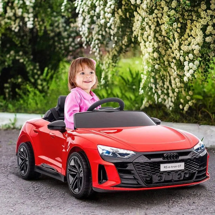 Child in a red Audi RS e-tron GT kids electric ride on car outdoors with flowers and greenery