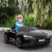 Child driving black 12V Audi RS e-tron GT kids ride-on car with LED lights outdoors