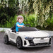 Child driving white licensed Audi RS e-tron GT kids ride on car outdoors under flowering trees