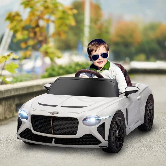 Child in white Bentley Bacalar kids electric ride-on car with butterfly doors and headlights on