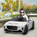 Child in white Bentley Bacalar kids electric ride-on car with butterfly doors and headlights on