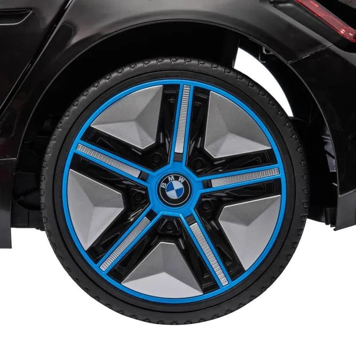 Close-up wheel of black 12V BMW i4 kids electric ride-on car with blue accents