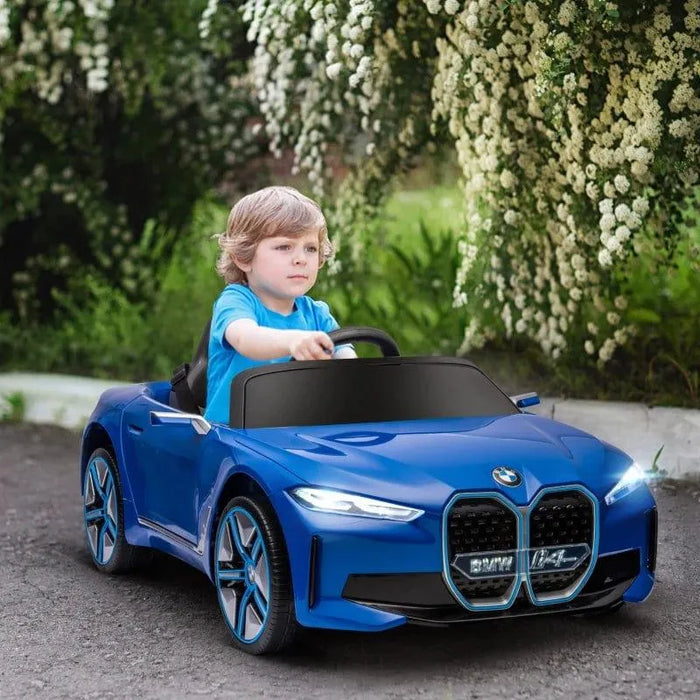 Child driving a blue 12V BMW i4 kids ride-on car outdoors, toy car with realistic details