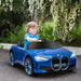 Child driving a blue 12V BMW i4 kids ride-on car outdoors, toy car with realistic details