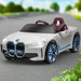 White 12V licensed BMW i4 kids ride on car with blue trim parked on road