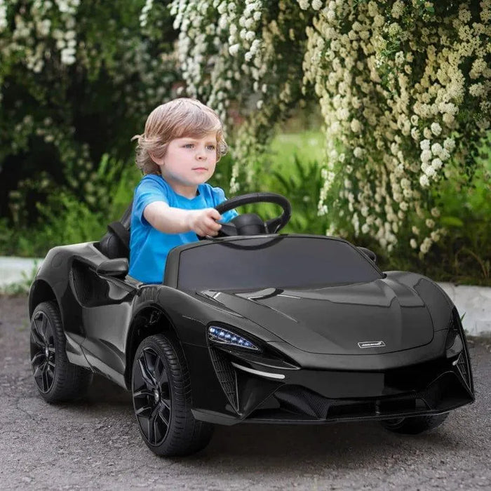Child driving 12V licensed black McLaren kids electric ride-on car outdoors, butterfly doors visible