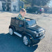 Child driving black Mercedes-Benz G500 kids ride-on jeep outdoors