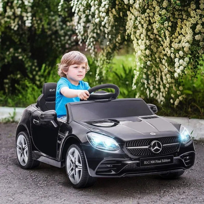 Child driving black Mercedes-Benz SLC 300 kids electric ride-on car with LED lights outside