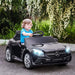 Child driving black Mercedes-Benz SLC 300 kids electric ride-on car with LED lights outside