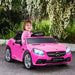 Smiling child driving pink Mercedes-Benz SLC 300 kids electric ride-on car outdoors