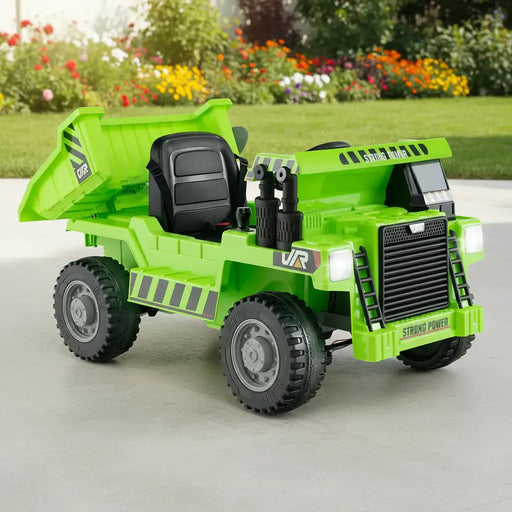 Green electric kids ride-on dump truck with black seat and large wheels on concrete surface