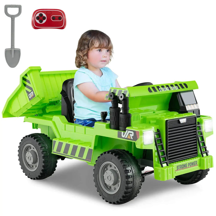 Child riding green electric toy dump truck with remote control and toy shovel