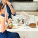 Couple enjoying a snack in a kitchen with a stand mixer on the counter.