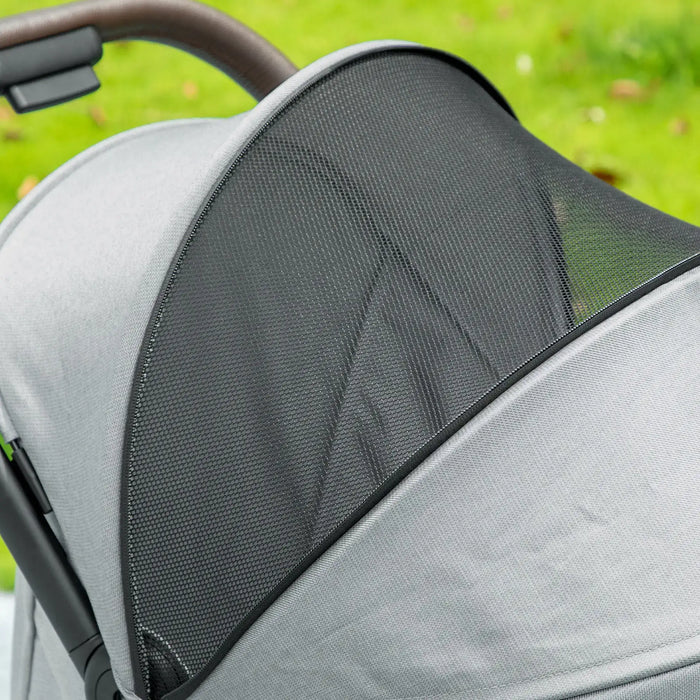 Close-up of a gray stroller with a mesh side panel on a grassy background