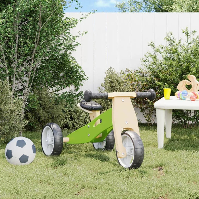 Green and black 2-in-1 convertible balance bike with adjustable seat in a backyard garden