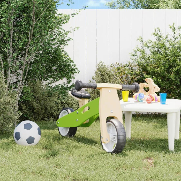 Green and black 2-in-1 convertible balance bike with adjustable seat in a grassy backyard