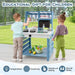 Two children play at a blue double-sided mud kitchen with canopy and toy kitchen accessories outdoors.