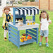Kids playing with blue double-sided mud kitchen and kitchen accessories outdoors