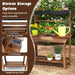 Wooden outdoor mud kitchen with double countertops, shelves, and gardening tools in a garden