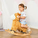 Toddler riding yellow plush giraffe 2-in-1 rocking horse with wheels indoors