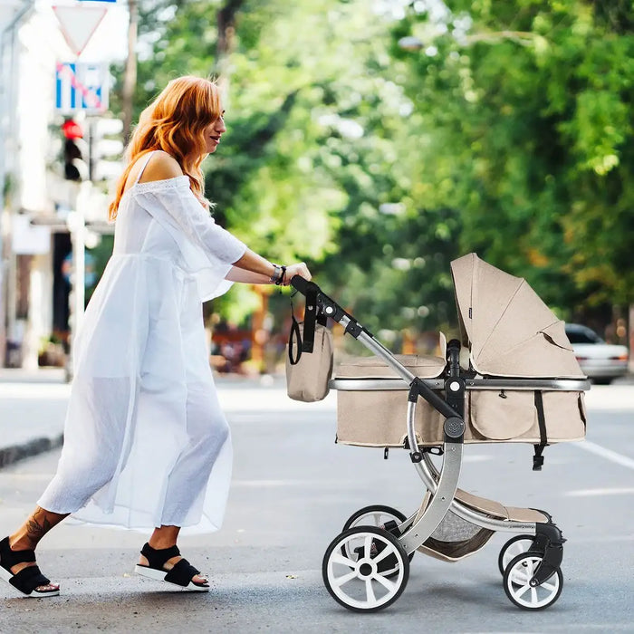 Woman pushing a beige stroller on a city street with greenery in the background