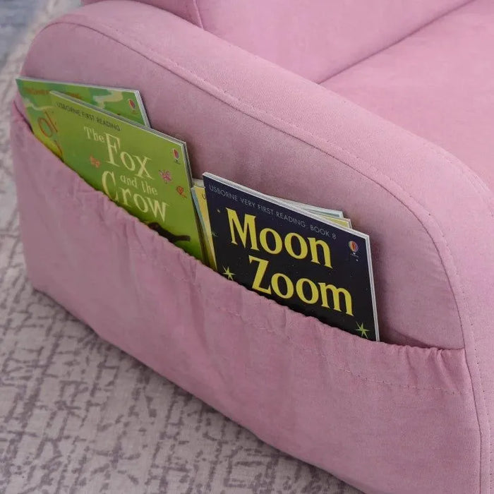 Pink kids chair with side pocket holding children's books on a patterned carpet