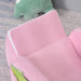 Pink 2-in-1 kids chair with white trim on carpet, partial green plush toy visible